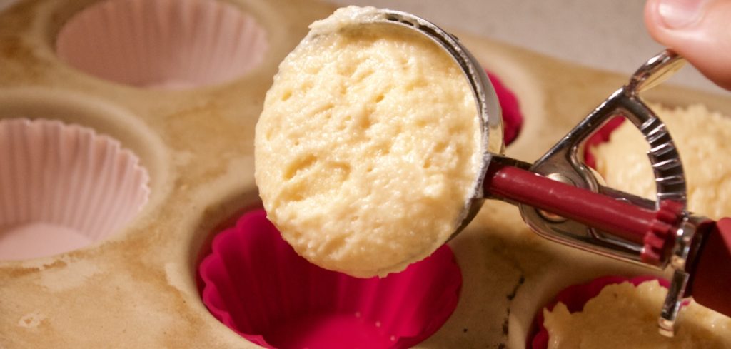 Cupcake batter scooped into muffin tray