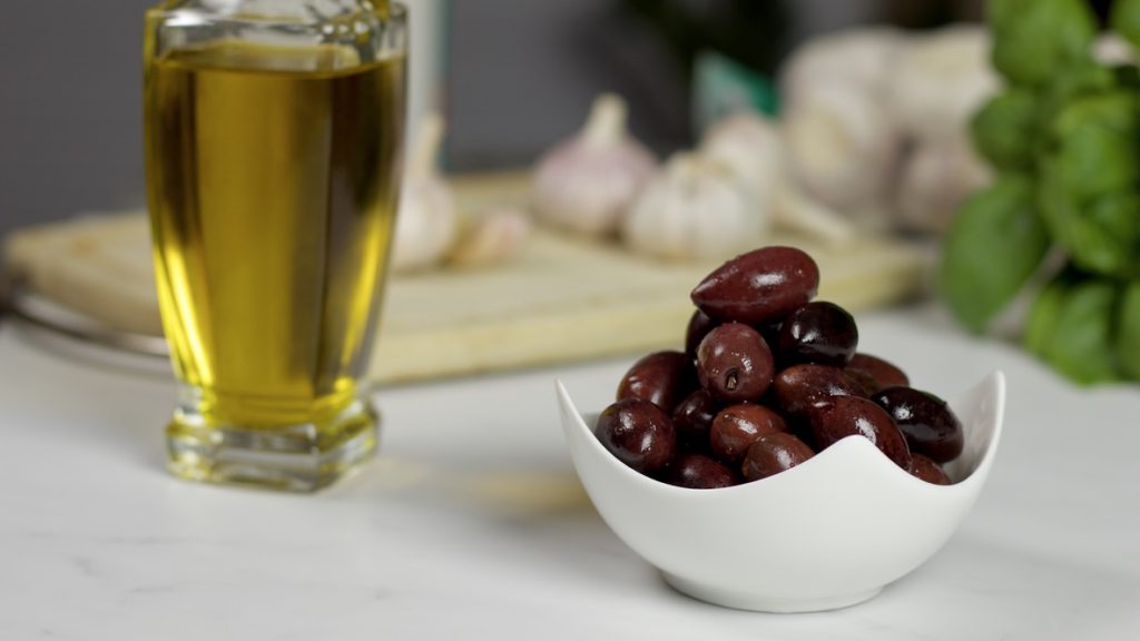 Fresh Olives and a glass jar with Olive Oil.