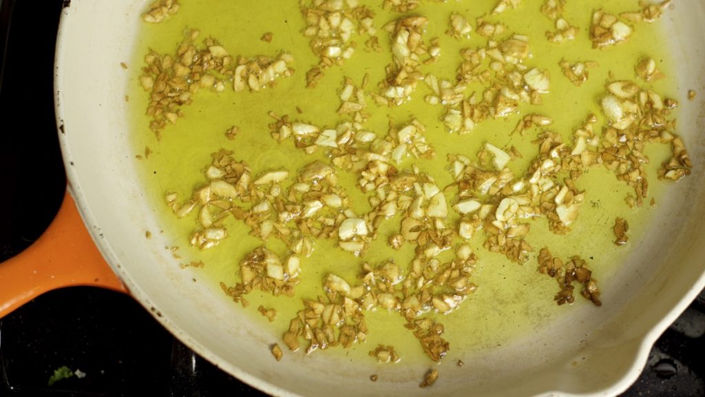 Brown Garlic in Olive Oil cooking in cast iron pan. 